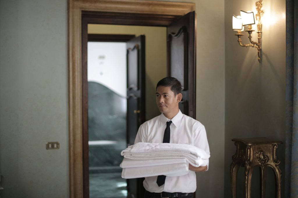 Hotel staff member carrying folded towels in hallway