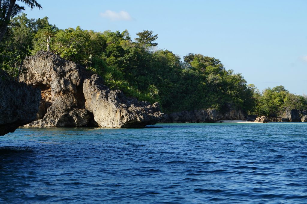 Rocky coastal cove on Guimaras Island with limestone cliffs and clear blue water.