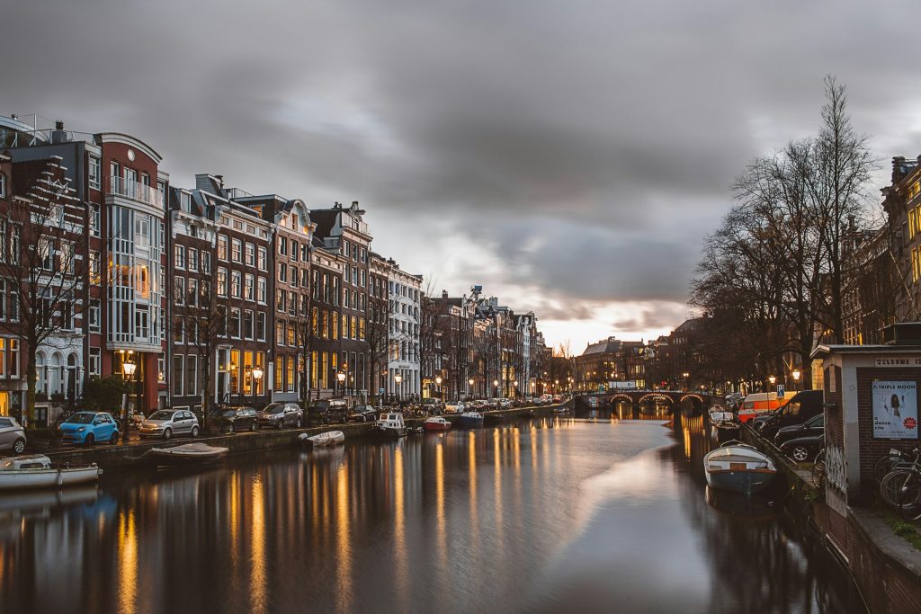 Amsterdam canal with historic houses and boats at dusk