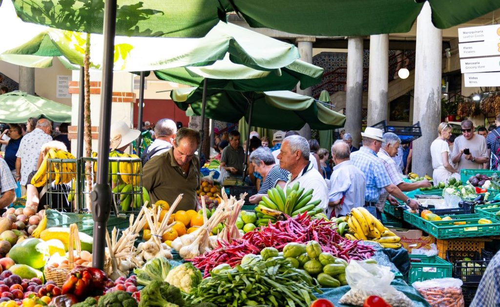 Local market in Funchal, Madeira with colorful stalls selling fresh produce, flowers, and traditional souvenirs.
