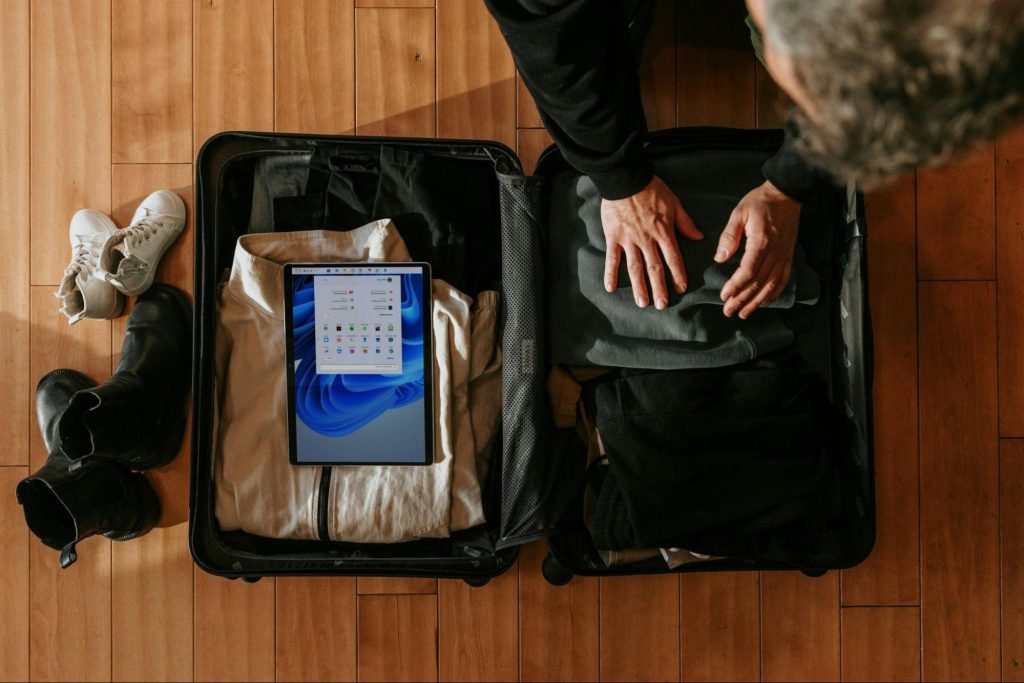 Traveler packing clothes and tablet into suitcase