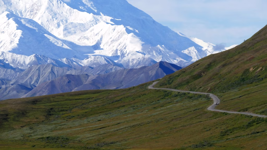 Winding mountain road in Alaska with snow-covered peaks in the background