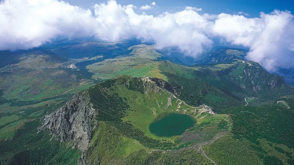 Aerial view of green mountains, a small crater lake and clouds in South Korea